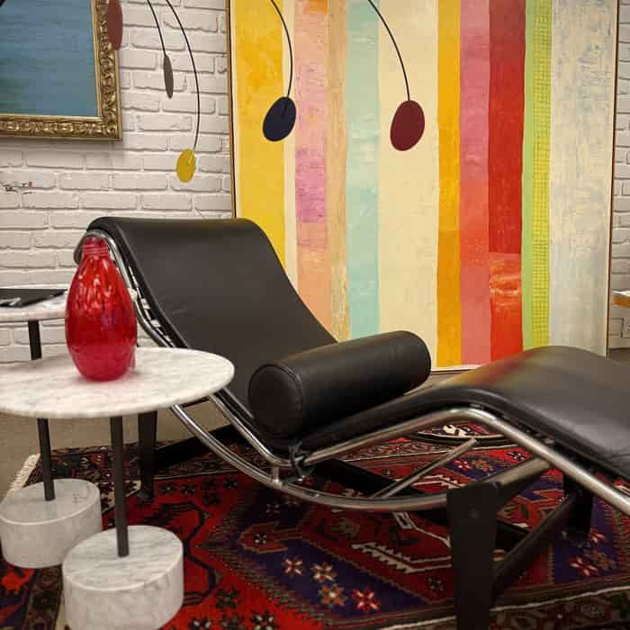 Modern black lounge chair in a room with colorful abstract art on the wall.