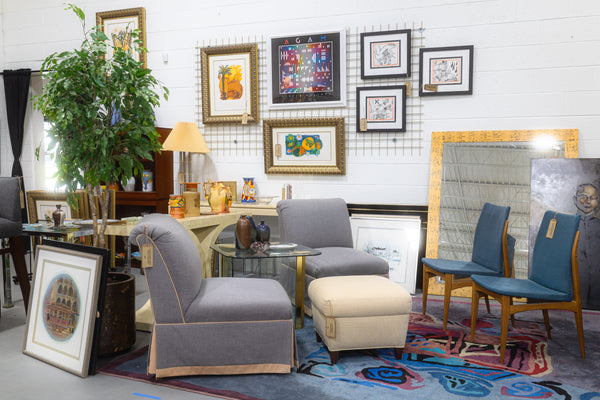 A photo of a vendor booth with a set of chairs and art scattered throughout