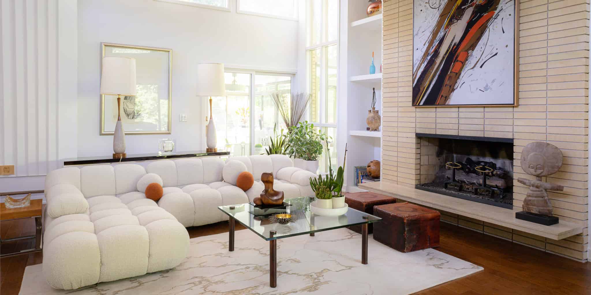 Modern living room with white sectional sofa, glass coffee table, and fireplace.