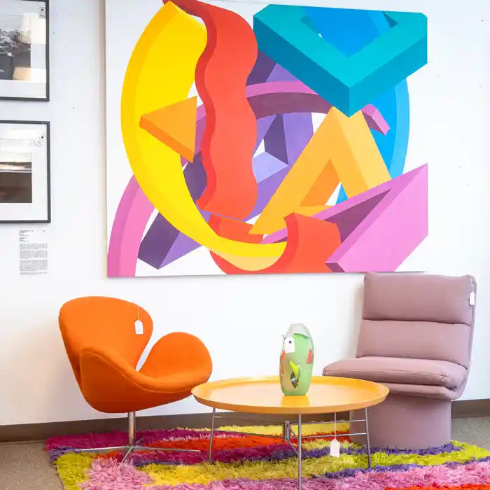 Modern living room with colorful abstract art, chairs, and a coffee table.