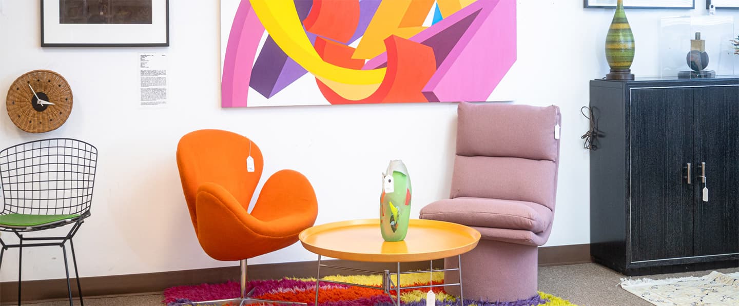 Modern living room with colorful furniture and abstract art on the wall.