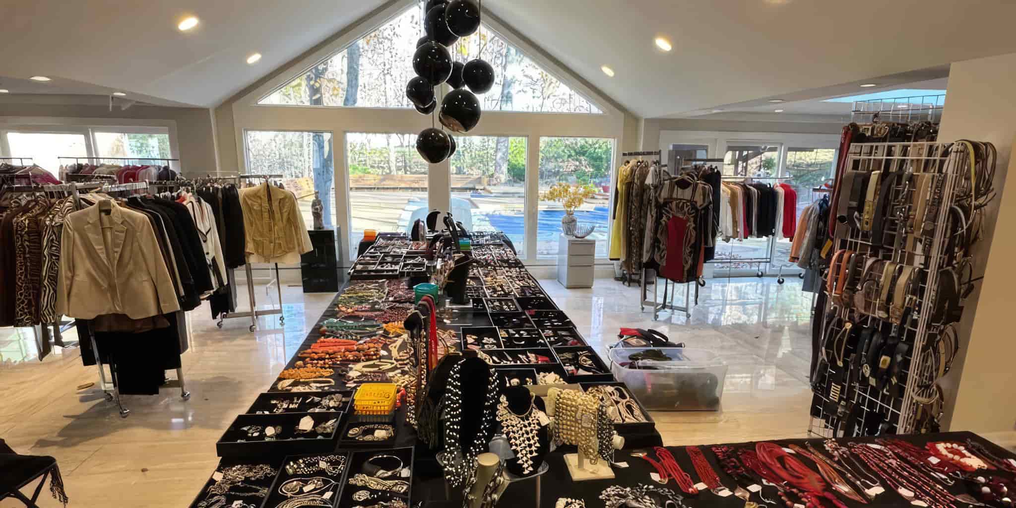 Interior of a housewith tables displaying accessories and racks of clothes.
