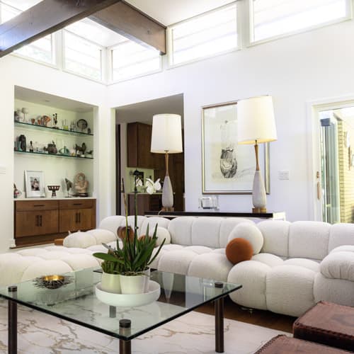 Modern living room with white sofa, glass coffee table, and decorative elements.